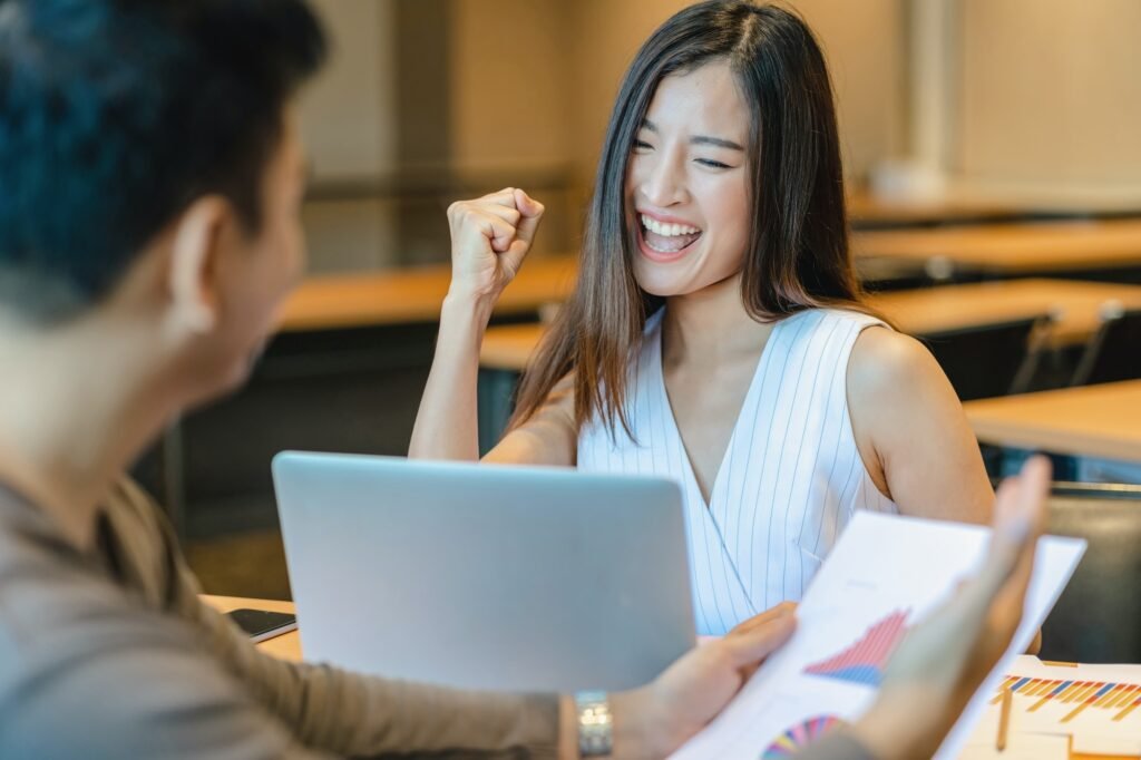 Rear view of Boss congratulating to asian businesswoman in glad action when successful